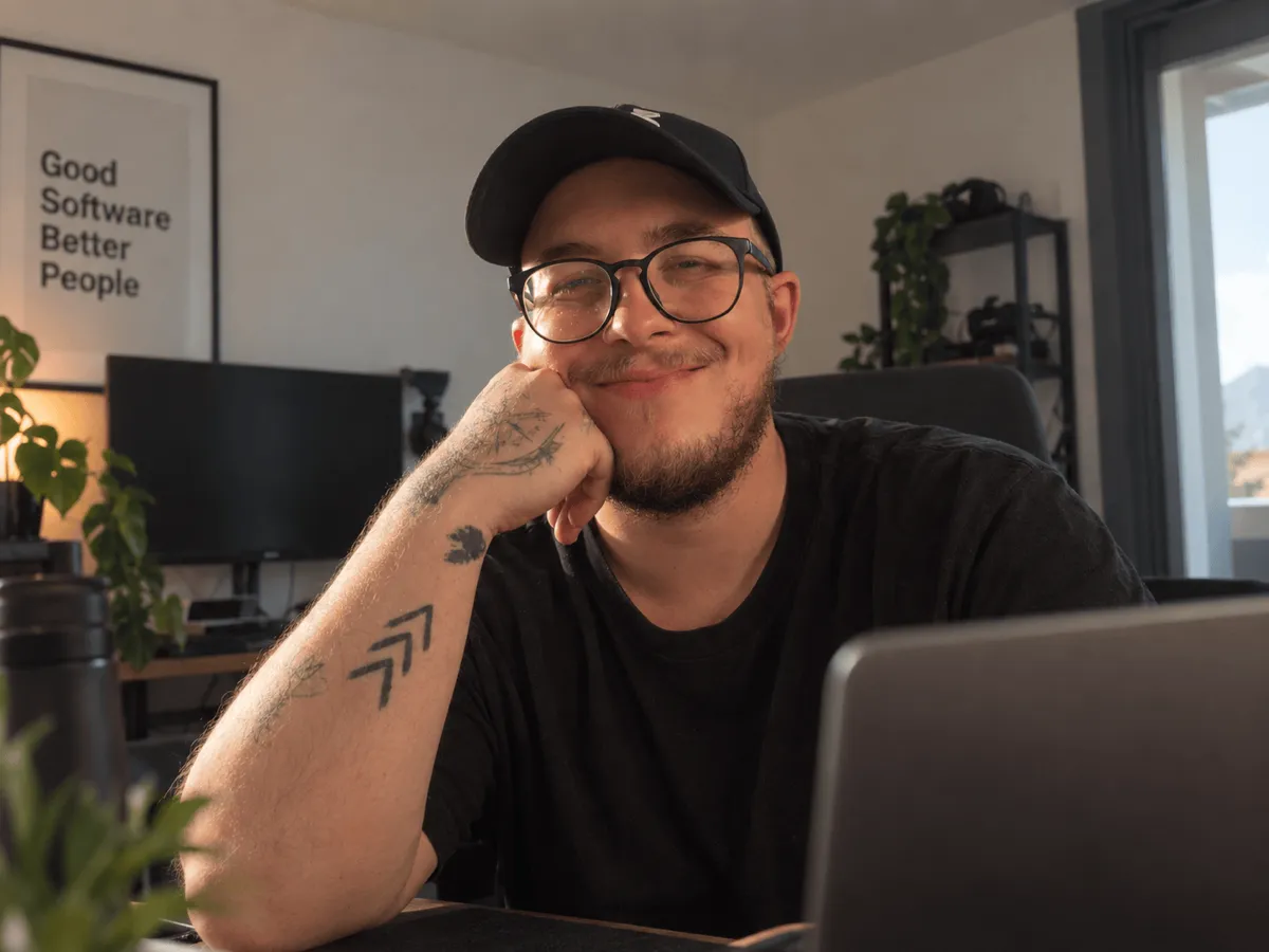 Raphael Planer an seinem Schreibtisch in Salzburg, lächelnd, das Kinn auf die Hand gestützt.